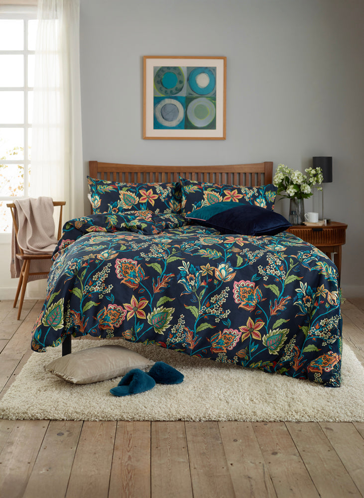 Bedroom with floral bedding, wooden headboard, and framed artwork on the wall.